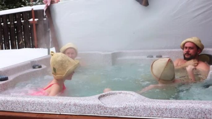 在寒冷的冬日，快乐快乐的有孩子的家庭喜欢在热水浴缸按摩浴缸里洗热水澡。