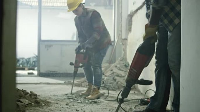 DS两名建筑工人用手提凿岩机拆除房屋的地板
