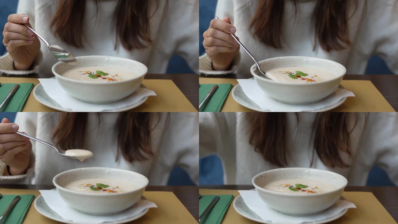 一个女人吃白奶油汤的特写镜头