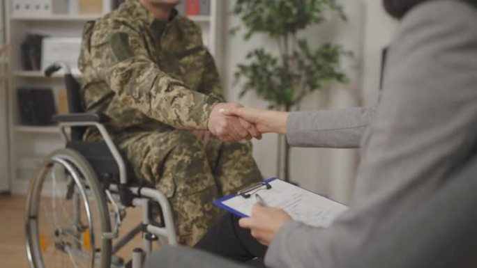 特写残疾士兵与心理医生握手，康复