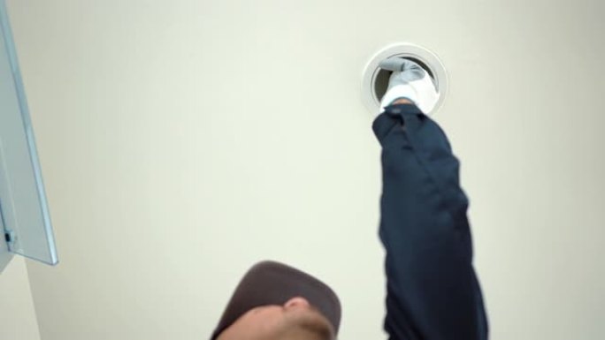 关闭电工在家里安装发光二极管灯泡以节省电力。修理改变公寓内的灯。居家服务理念。