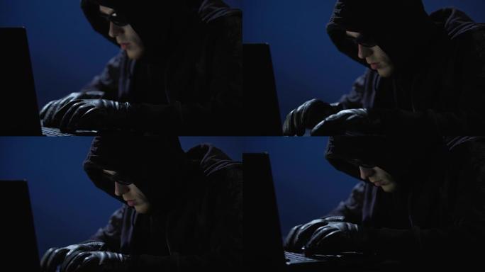 穿着黑衣，戴着墨镜和手套的奇怪男子正在从笔记本电脑中窃取数据