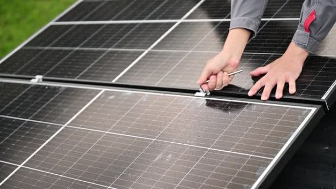 男子技术人员在六角钥匙的帮助下将光伏太阳能电池板安装在房屋屋顶上。