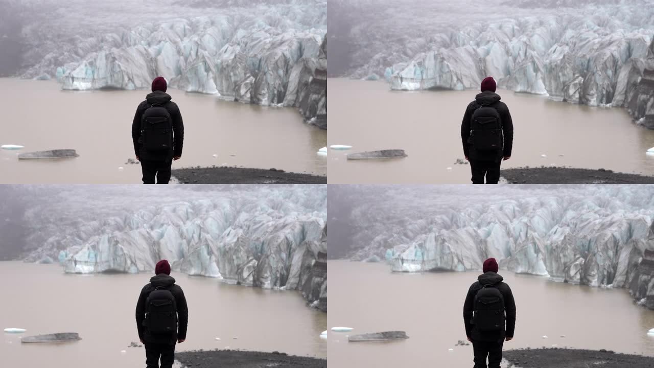 一个男人看着Svinafellsjokull冰川的背景图