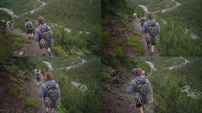 徒步旅行者的队伍沿着树木繁茂的小径驶向山涧