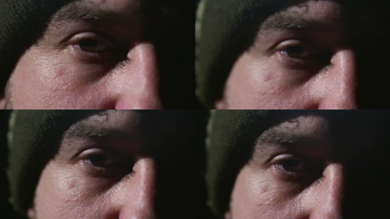 一个男人的眼睛在一个绿色的帽子在黑色的背景。人造光宏。一个乌克兰士兵的特写镜头。