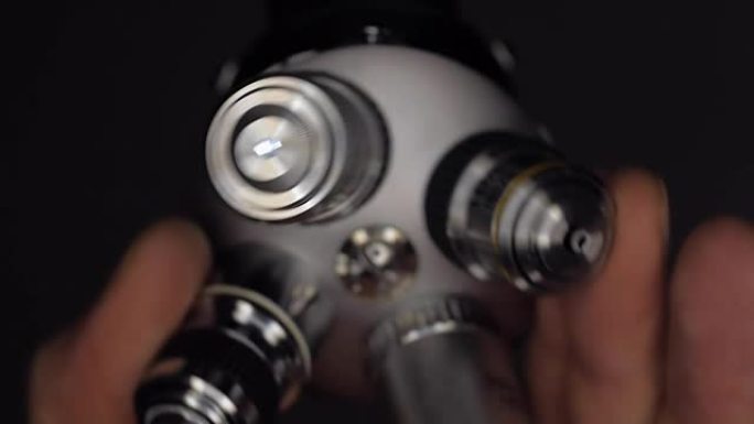 一只手旋转一块显微镜镜头，其中一个明亮地发光