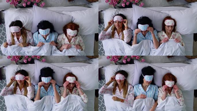 俯视图，三个漂亮的女孩在母鸡之夜和一个很棒的聚会后上床睡觉，戴上眼圈绷带睡觉