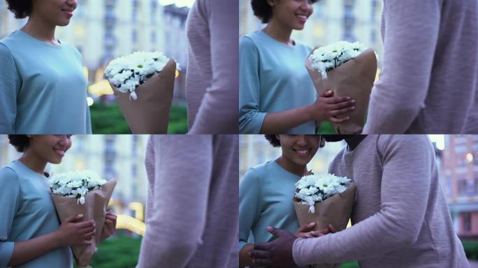 充满爱心的男人向漂亮的女友献花，在夏日约会之城拥抱
