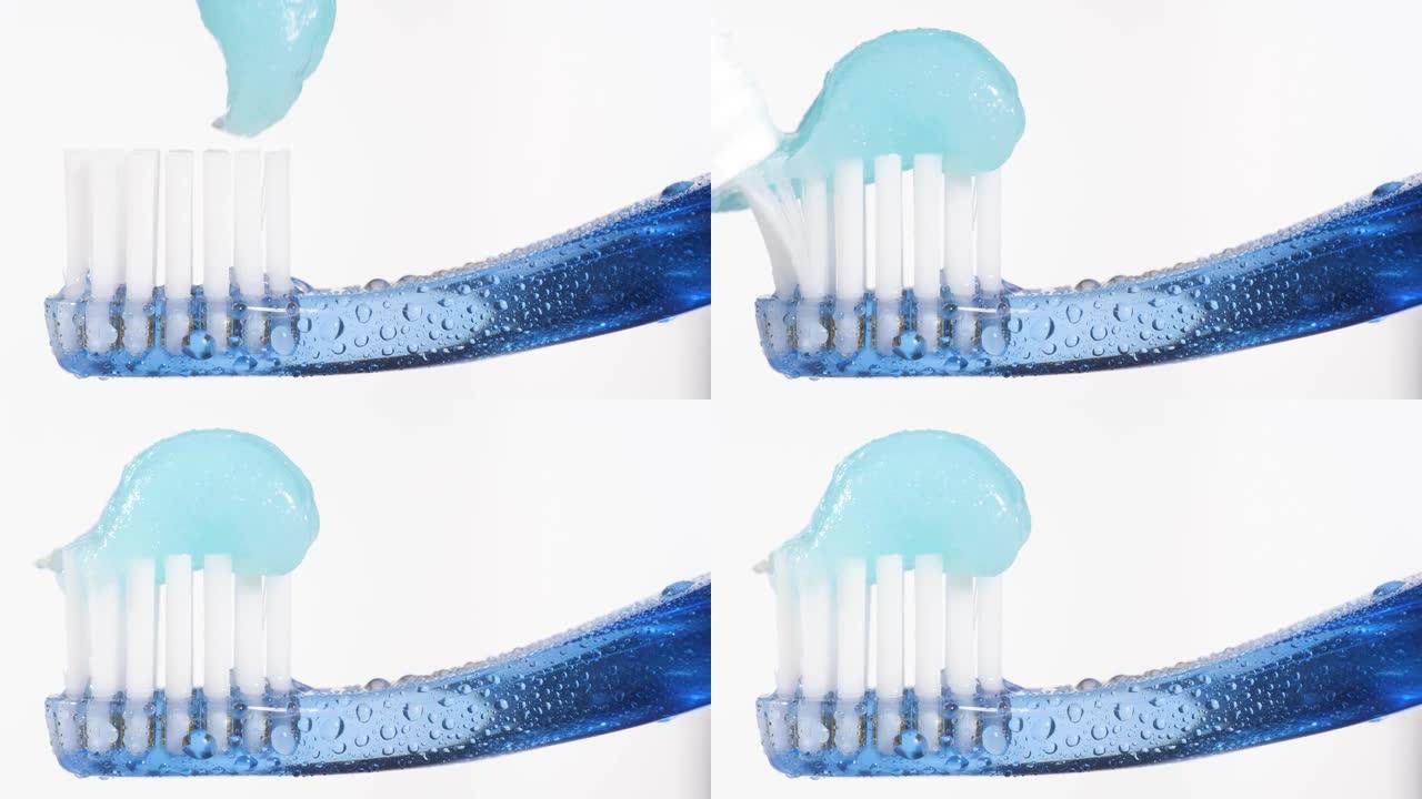 牙刷和牙膏。蓝色牙刷的宏观视图，蓝色牙膏被挤压在白色背景上。慢动作
