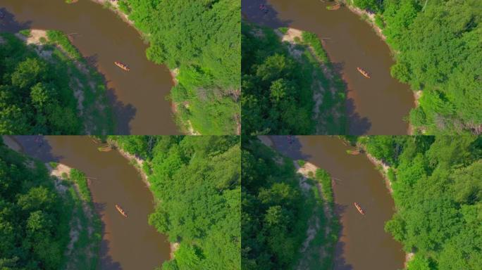 一大群彩色皮划艇，游客在河边划着划着一条急弯的河。在平静的河流上乘独木舟进行水上旅游，流经森林的平坦