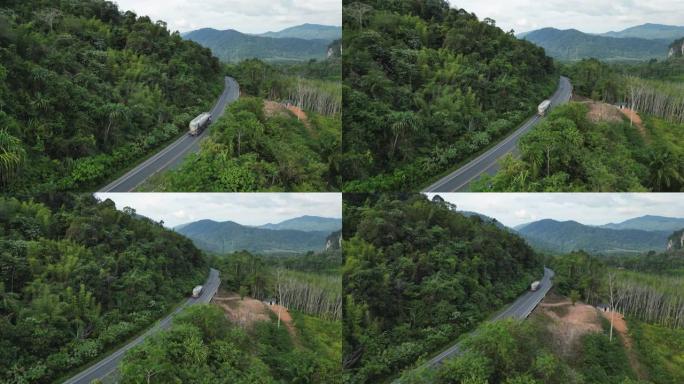 穿过棕榈油树种植园的卡车在道路上的鸟瞰图