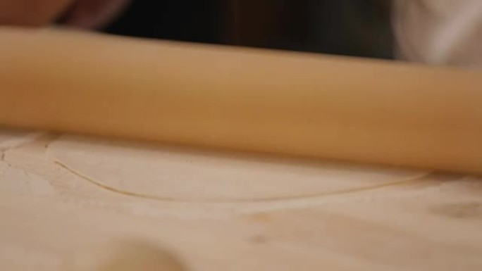 Experienced woman rolling dough with pin
