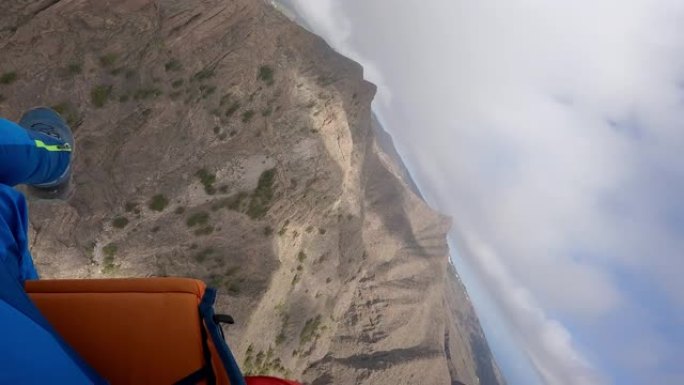 滑翔伞在崎rock的岩石地形上飞行的前视图