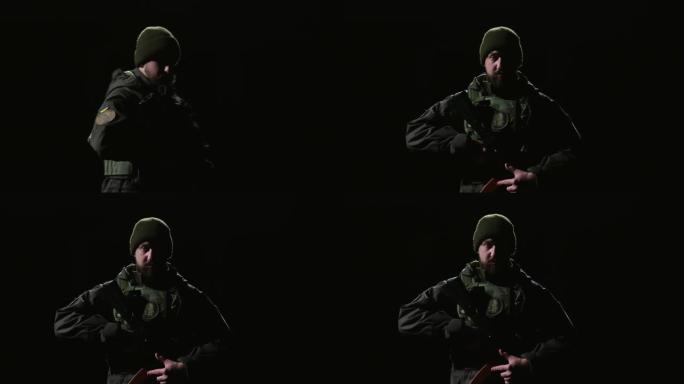 一名大胡子的国民自卫军士兵手里拿着武器，走进黑色背景的画框，看着镜头。乌克兰战争的特工
