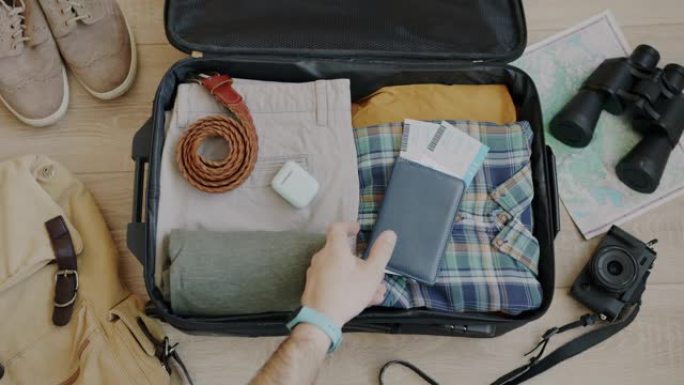手工将护照和机票放在度假手提箱包装袋中的俯视图
