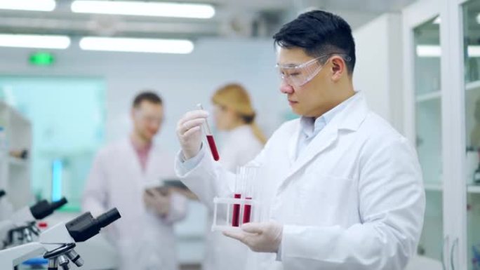 医学研究员科学家亚洲男子与同事一起在试管中保存血液样本HIV或细菌测试