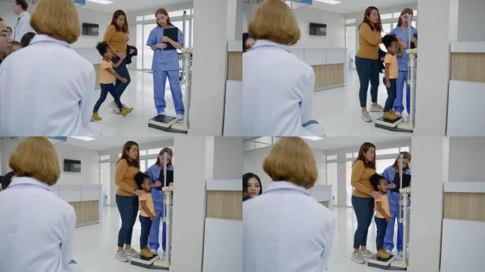 护士带孩子在医院里称体重并测量他的身高。