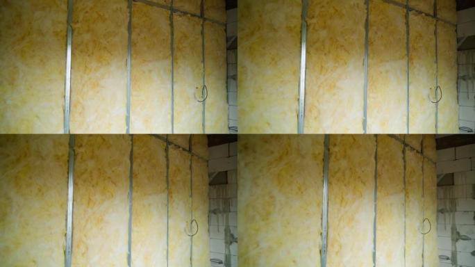 玻璃棉绝缘和隔音。从U形轮廓沿内墙的框架充满了通用绝缘，特写。平稳的摄像机运动