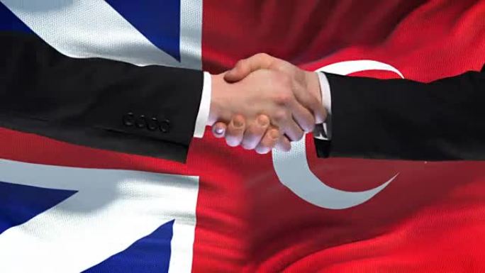 英国和土耳其握手，国际友谊，旗帜背景