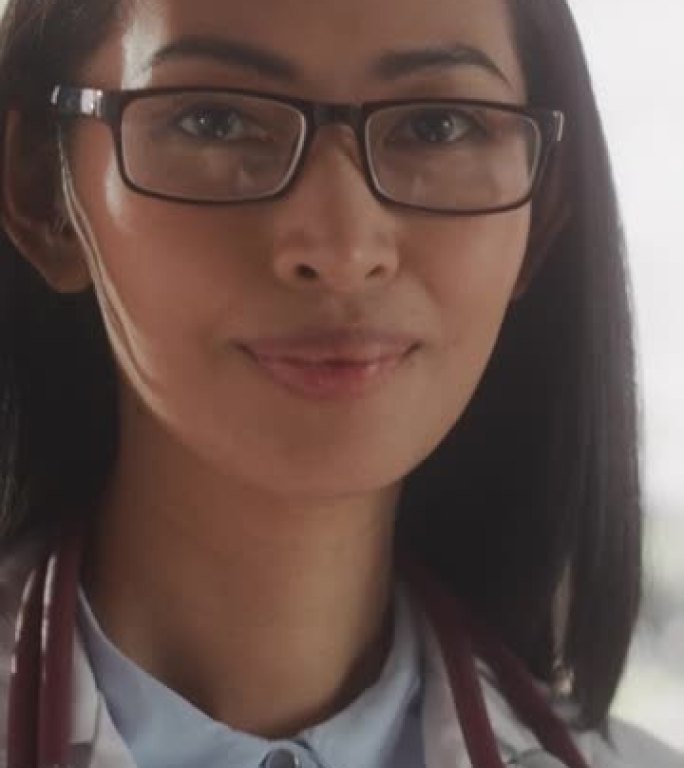 垂直屏幕: 一位美丽的医疗保健专业人员摆姿势，微笑着看着相机的肖像。亚洲诊所医师戴眼镜穿白大褂在医院