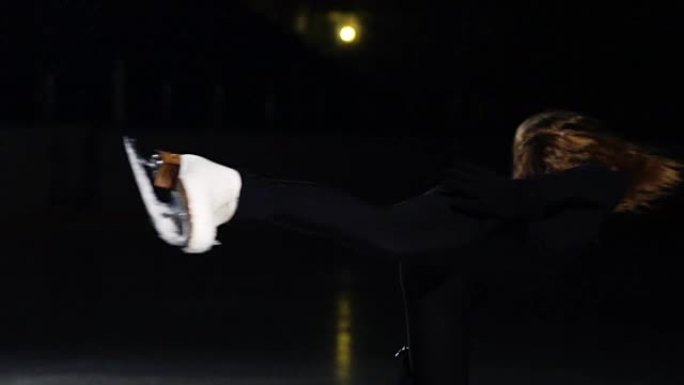 一个女孩滑冰运动员在冰上的特写镜头围绕她的轴旋转，同时以燕子姿势站在冰上的一条腿上。蹲到手枪的位置继