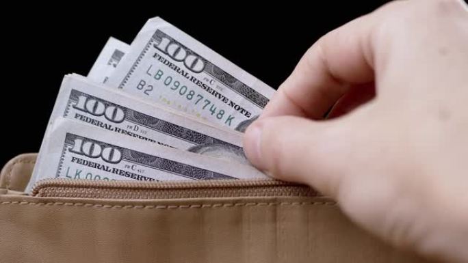 女性手从棕色皮革钱包里拿出100美元钞票，数数