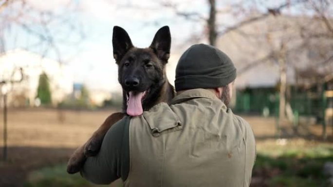 面目全非的教练手拿一只年轻的德国牧羊犬走路