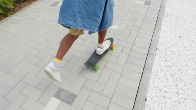 黑人男孩学习在人行道上骑滑板