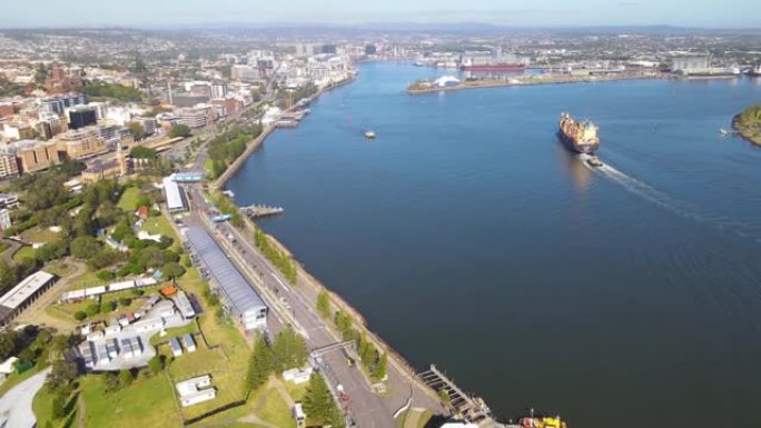在阳光明媚的日子里，一艘货船在新南威尔士州纽卡斯尔的海港市穿越纽卡斯尔港的空中无人机视图