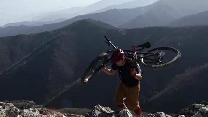 山地自行车手将自行车带到岩石山脊，到山顶