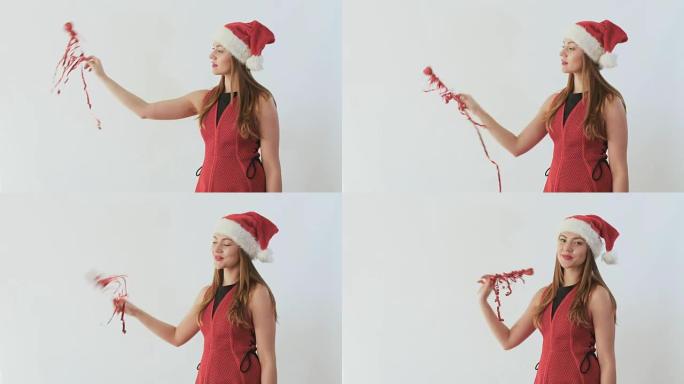 戴着圣诞老人帽子的可爱女孩用心和丝带挥舞装饰棒