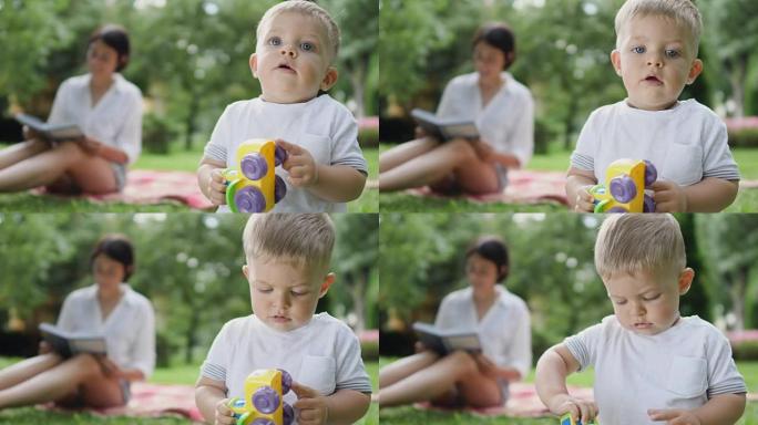 男孩玩玩具，妈妈在模糊的背景上看书