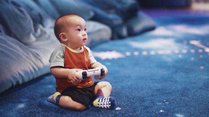 可爱的男婴使用游戏控制器在客厅玩视频游戏