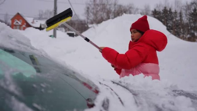 女人清理汽车上的积雪