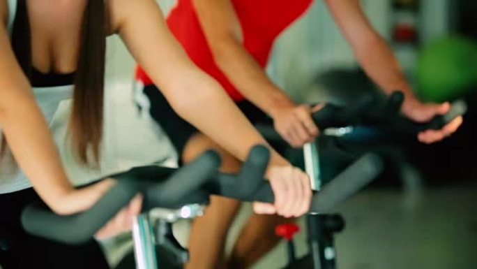 特写-男女在健身房健身自行车上训练