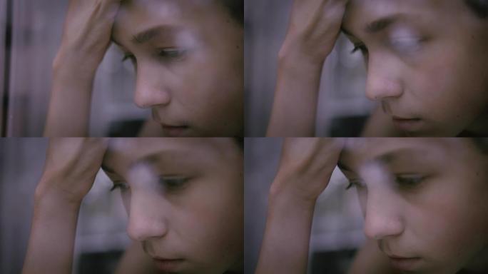 一个悲伤的男孩的肖像看着窗外，孤独，思考，移动相机，电影拍摄