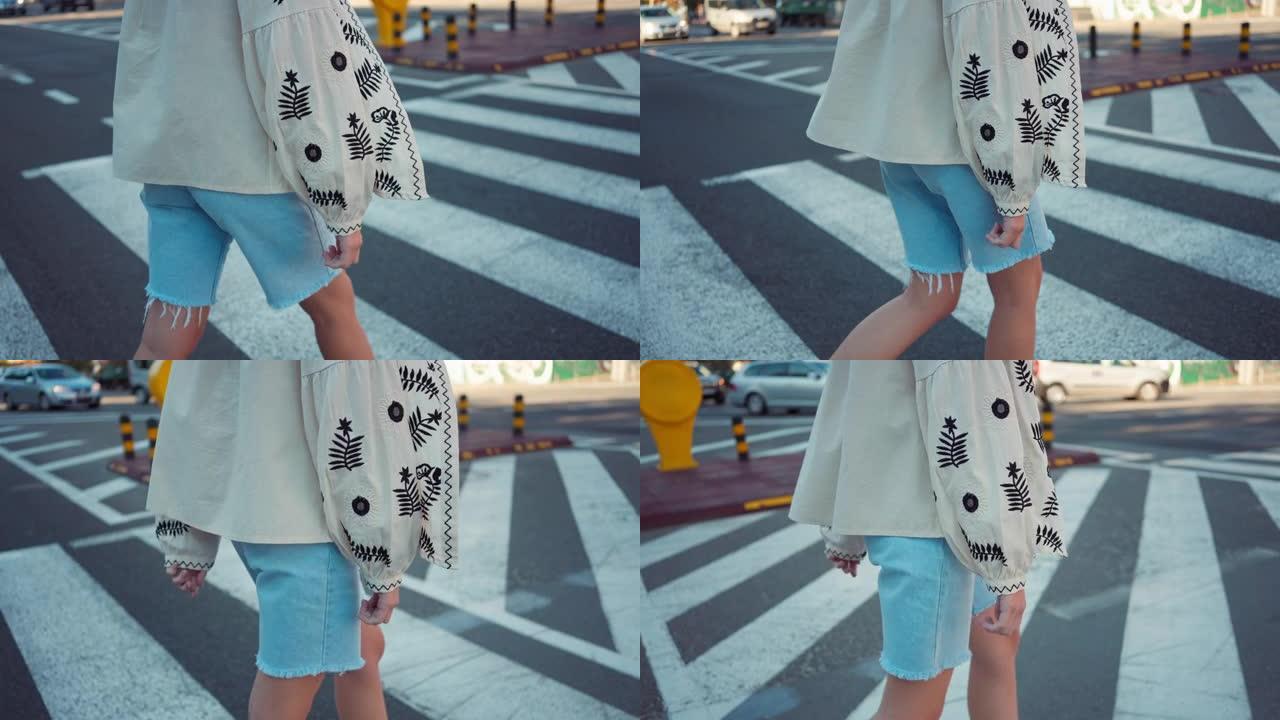 追踪镜头无法辨认的少女穿着刺绣乌克兰衬衫走在城市的人行横道上。侧视图少年在户外慢动作过马路。