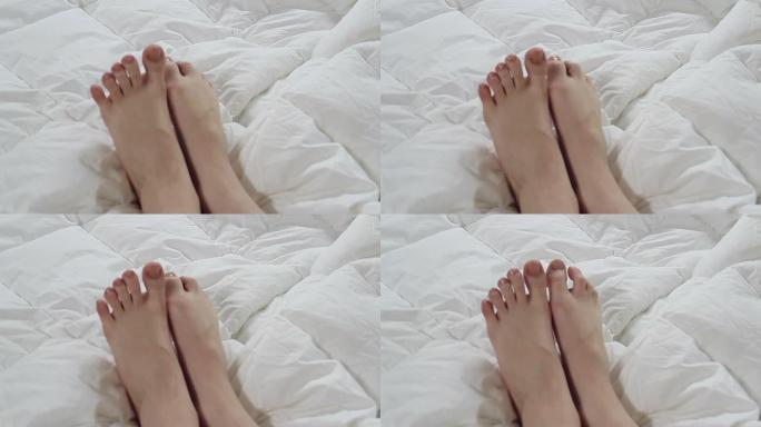 精致的女性脚在白色床上嬉戏地移动脚趾