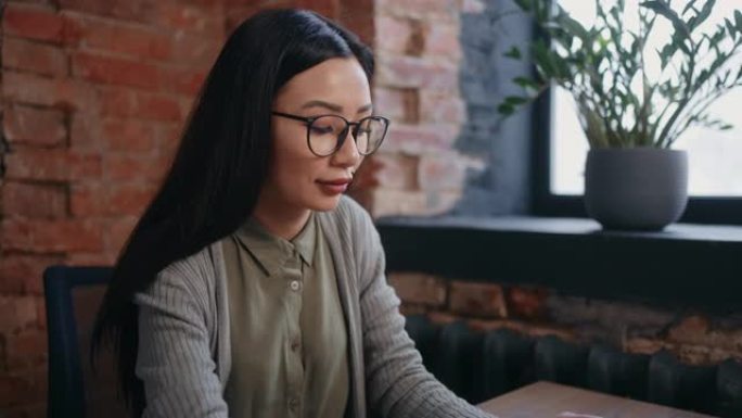 美丽的亚洲女人在办公室工作，看着电脑显示器，查看销售报告