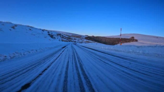 黄昏时在雪山路上行驶。