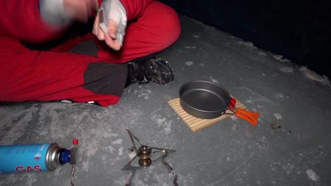 一个人在冰洞里用煤气做饭。