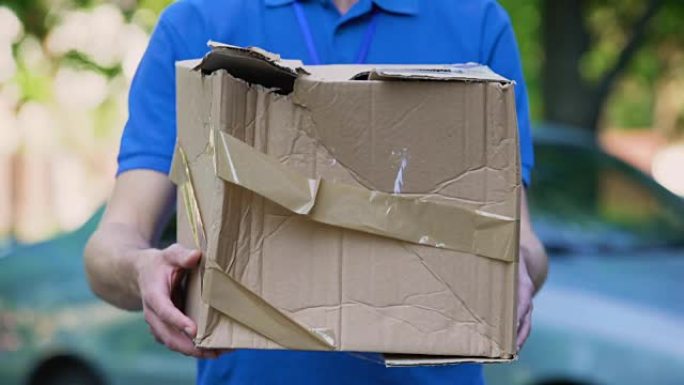 男性快递员显示箱子损坏，包裹运送便宜，装运质量差