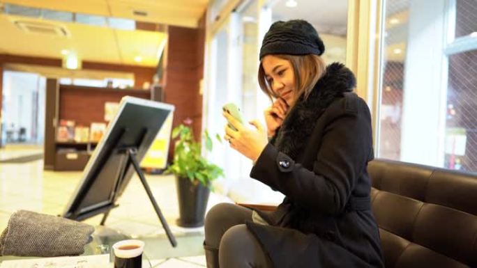 女人坐在酒店大堂使用智能电话视频通话