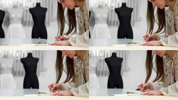 美丽的女孩时装设计师在穿着婚纱的模特上剪出布料的纸张模板。婚纱制造商