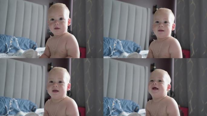 特写快乐俏皮昏昏欲睡的孩子10个月大。刚出生的男孩在白色柔软的床上洗完澡后看着相机。婴儿睡前打哈欠时