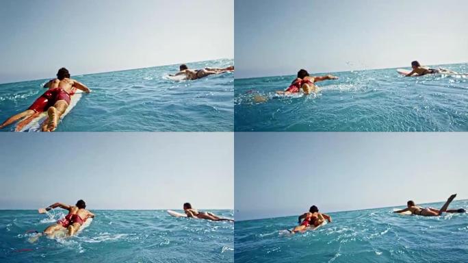 SLO MO两名海浪冲浪者在冲浪板上划入大海