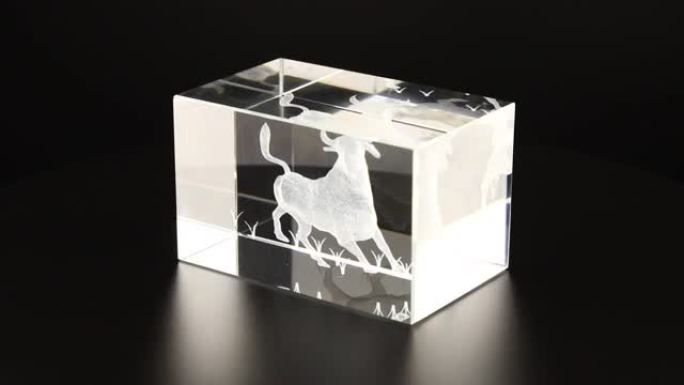描绘公牛的矩形玻璃块在黑色背景上旋转。