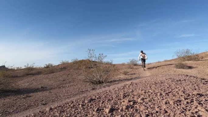 年轻人沿着沙漠小径骑自行车