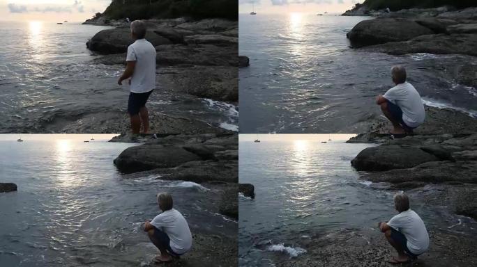 人下降到沿海岩石，望向日出
